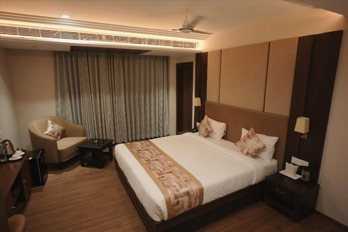 A hotel room with a large bed, a sofa, a desk, and a ceiling fan.