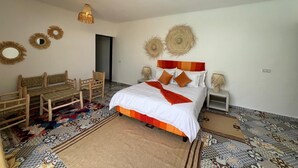A bedroom with a bed, two nightstands, a woven headboard, a woven floor lamp, and a patterned rug. - Family villa, private pool, not overlooked (Marrakech)
