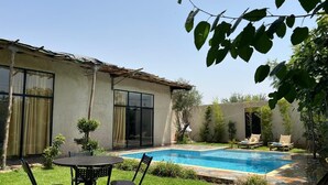 A backyard with a swimming pool, a patio table with chairs, and a small garden. - Family villa, private pool, not overlooked (Marrakech)