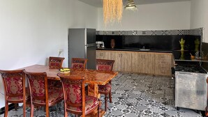 A dining area with a wooden table and chairs, a kitchen with a black countertop, and patterned flooring. - Family villa, private pool, not overlooked (Marrakech)