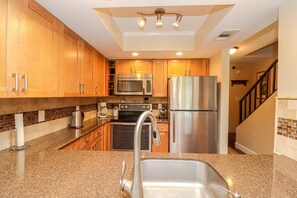 A kitchen with wooden cabinets, stainless steel appliances, a granite countertop, and a built-in oven. - Walk to St. Augustine Beach | Poolside Patio (St. Augustine)