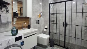 Ein modernes Badezimmer mit integrierter Waschmaschine, Waschbecken und Duschkabine.