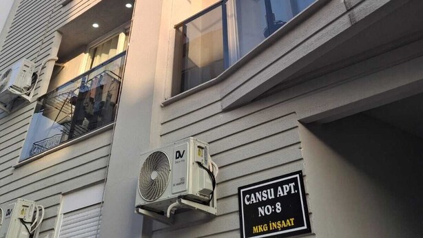 Ein mehrstöckiges Gebäude mit Balkonen und Klimaanlagen, mit dem Schild "CANSU APT. NO:8".