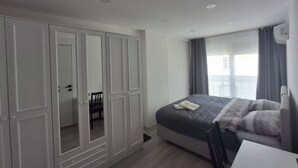 A bedroom with a bed, a wardrobe, a chair, and a desk.