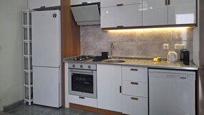 Eine moderne Küche mit weißen Schränken, einem Backofen, einer Spülmaschine und einem Gasherd.