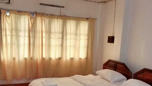 Una camera d'albergo con un letto grande, una testiera in legno e una finestra con tende.