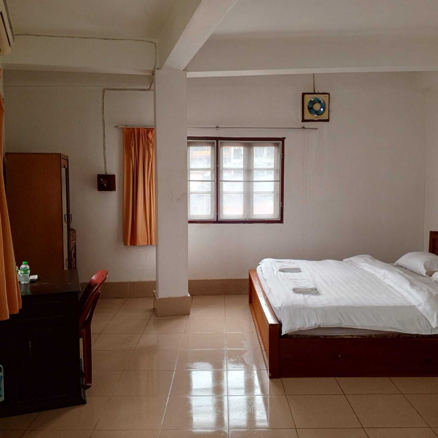 Een hotelkamer met een bed, een bureau, een stoel, een kledingkast en een raam.