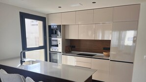 Una cocina moderna con una isla central, electrodomésticos integrados y un amplio ventanal.
