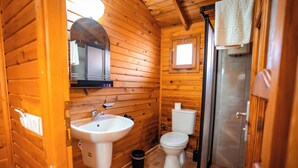 A wooden cabin bathroom with a sink, toilet, and shower. - Portakal Bahçesi Bungalow (Kumluca)