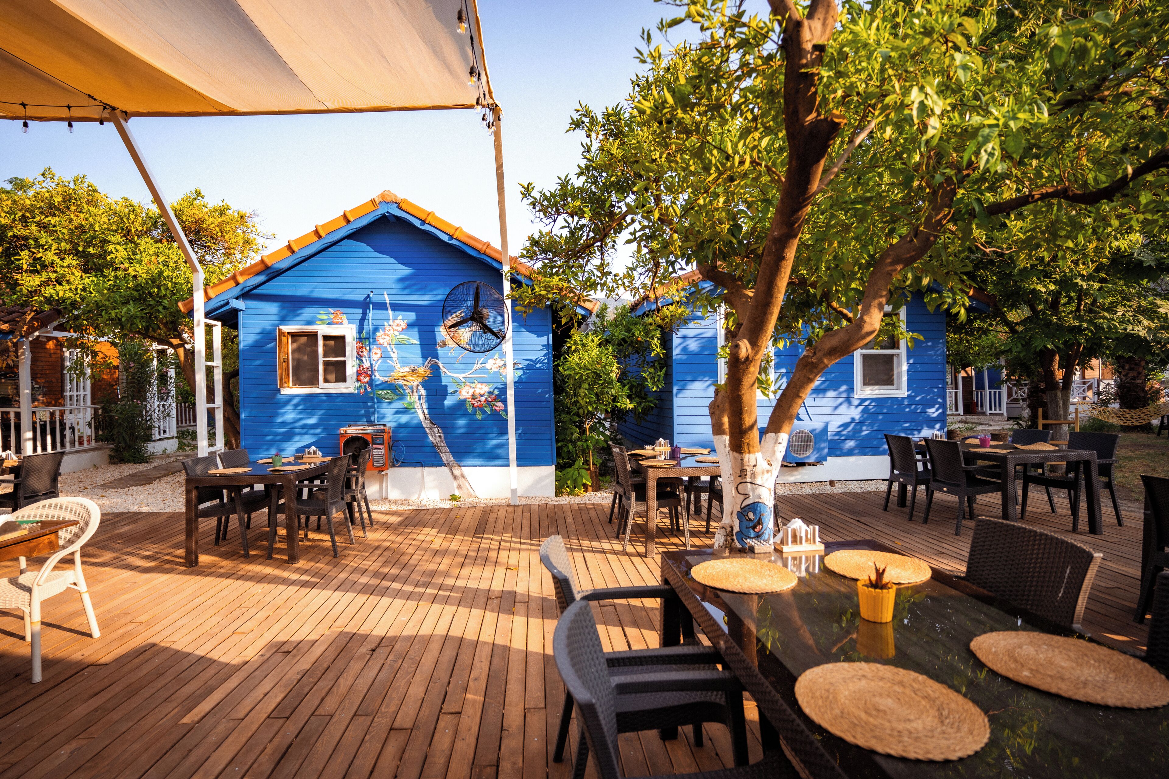 A blue house with a fan, outdoor seating, and a wooden deck.