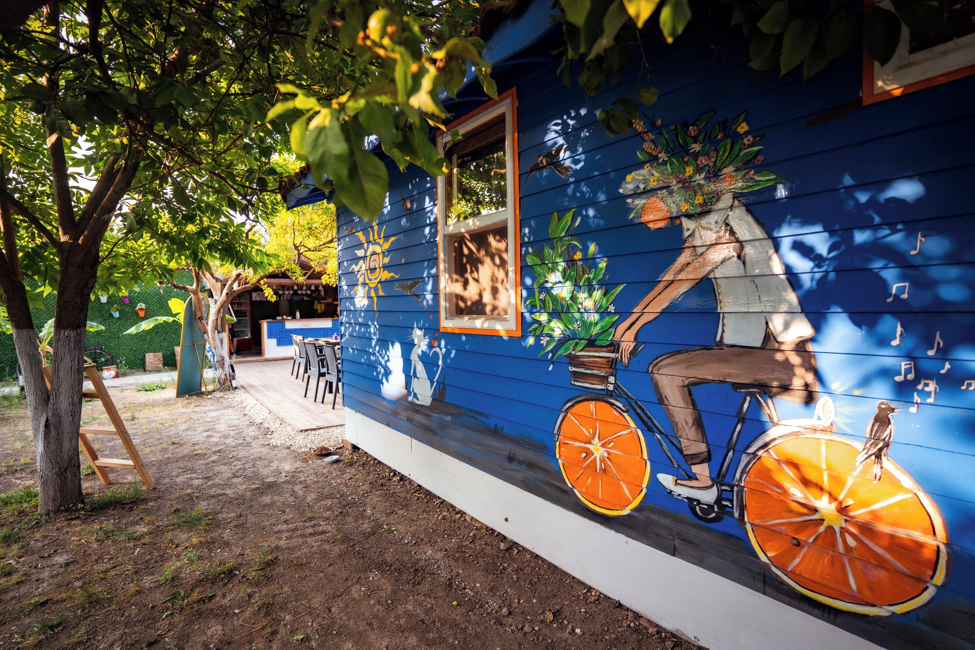 Un bâtiment bleu orné d’une fresque représentant une personne à vélo, dont la roue est une tranche d’orange.