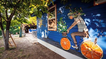 Un bâtiment bleu orné d’une fresque représentant une personne à vélo, dont la roue est une tranche d’orange.