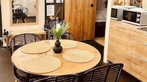 A dining area with a round table, black chairs, a potted plant, and a wooden cabinet with a microwave. - ASTORIA Loft Elite Apartment free parking,AC,Elevator (Budapest)