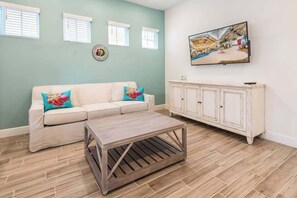 A living room with a sectional sofa, a coffee table, a cabinet, and a painting on the wall.