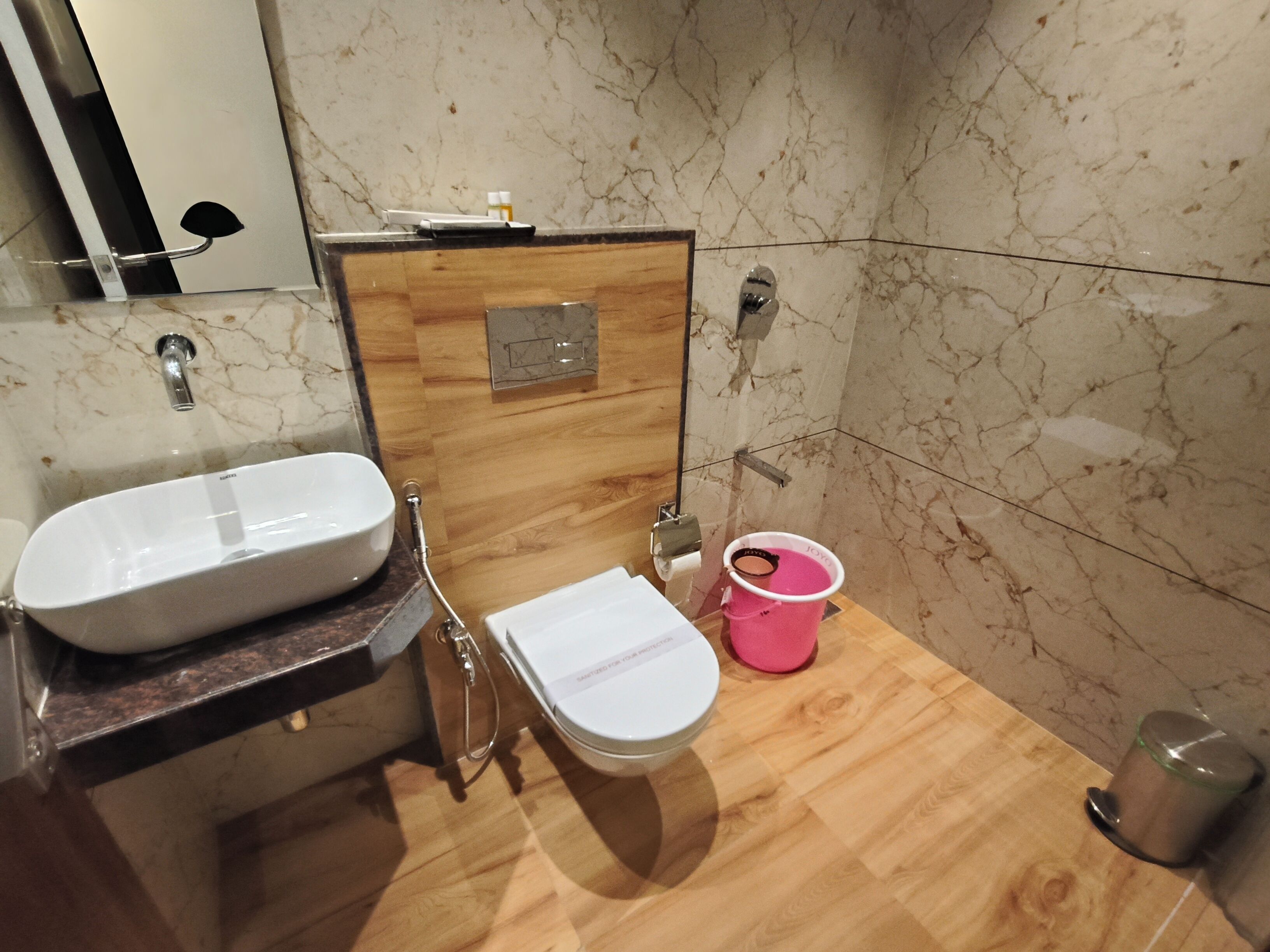 A bathroom with a wooden vanity, a white sink, and a toilet.