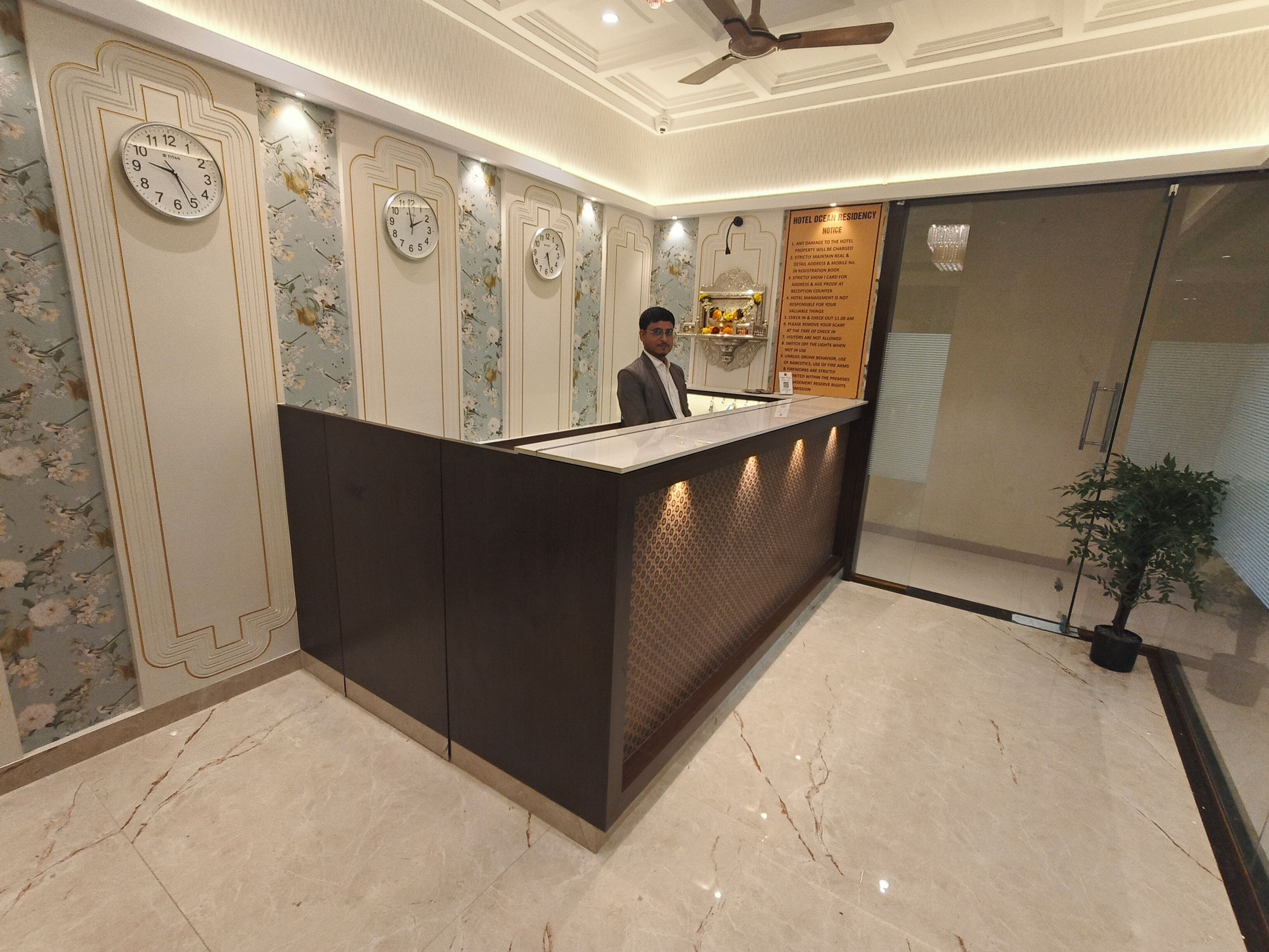A hotel reception area with a modern design, featuring a reception desk, multiple wall clocks, and a reception counter.