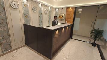 A hotel reception area with a modern design, featuring a reception desk, multiple wall clocks, and a reception counter.