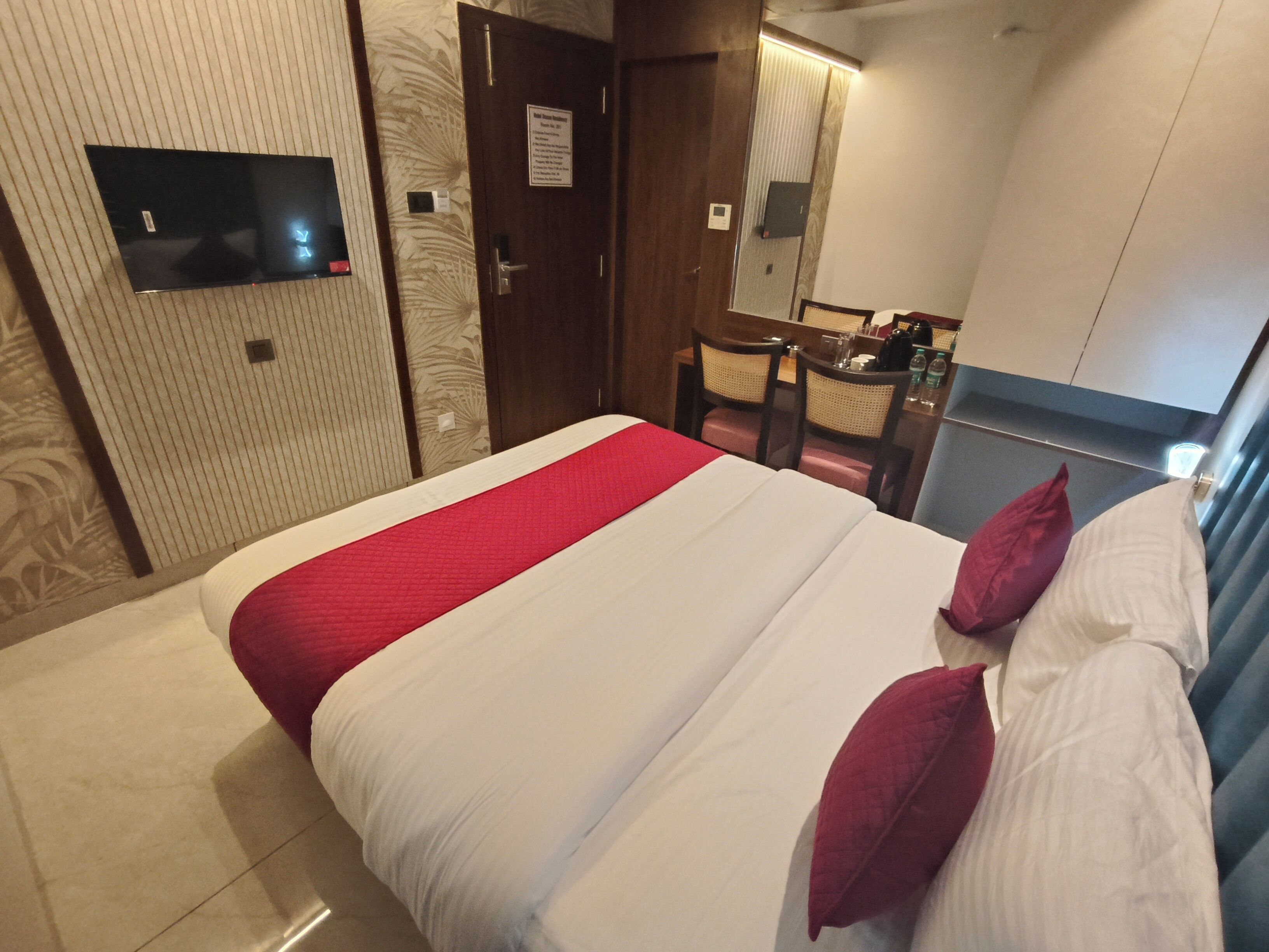 A hotel room with a bed, a desk, and a mirror.