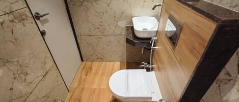 A modern bathroom with a wooden vanity, a white sink, and a toilet.