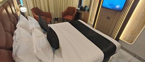 A hotel room with a large bed, a TV on the wall, a small table, and two chairs.