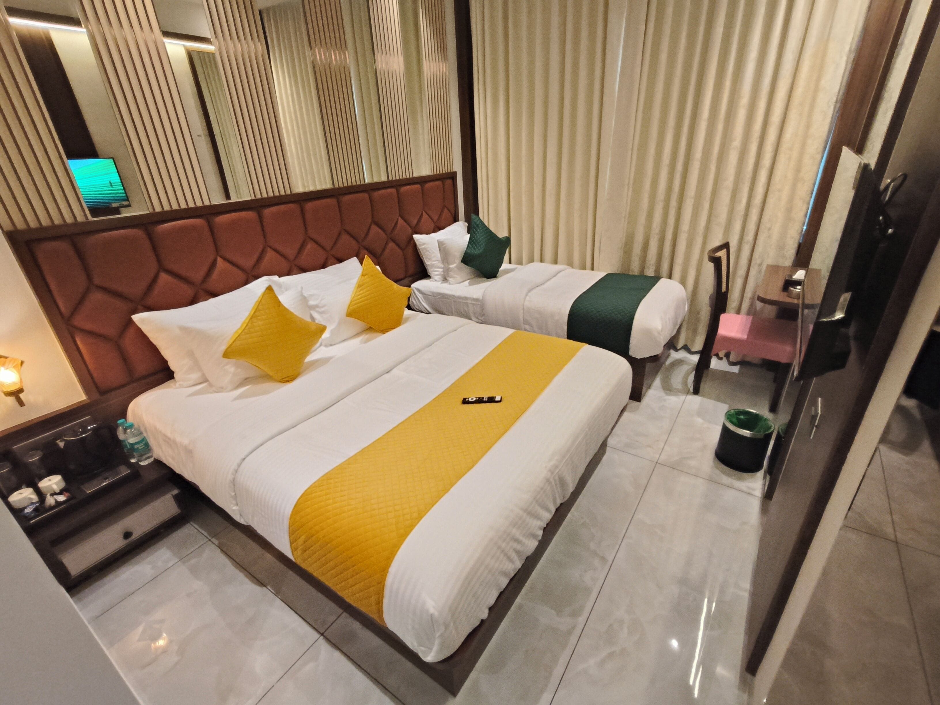 A hotel room with two beds, a nightstand, a desk, and a bathroom.