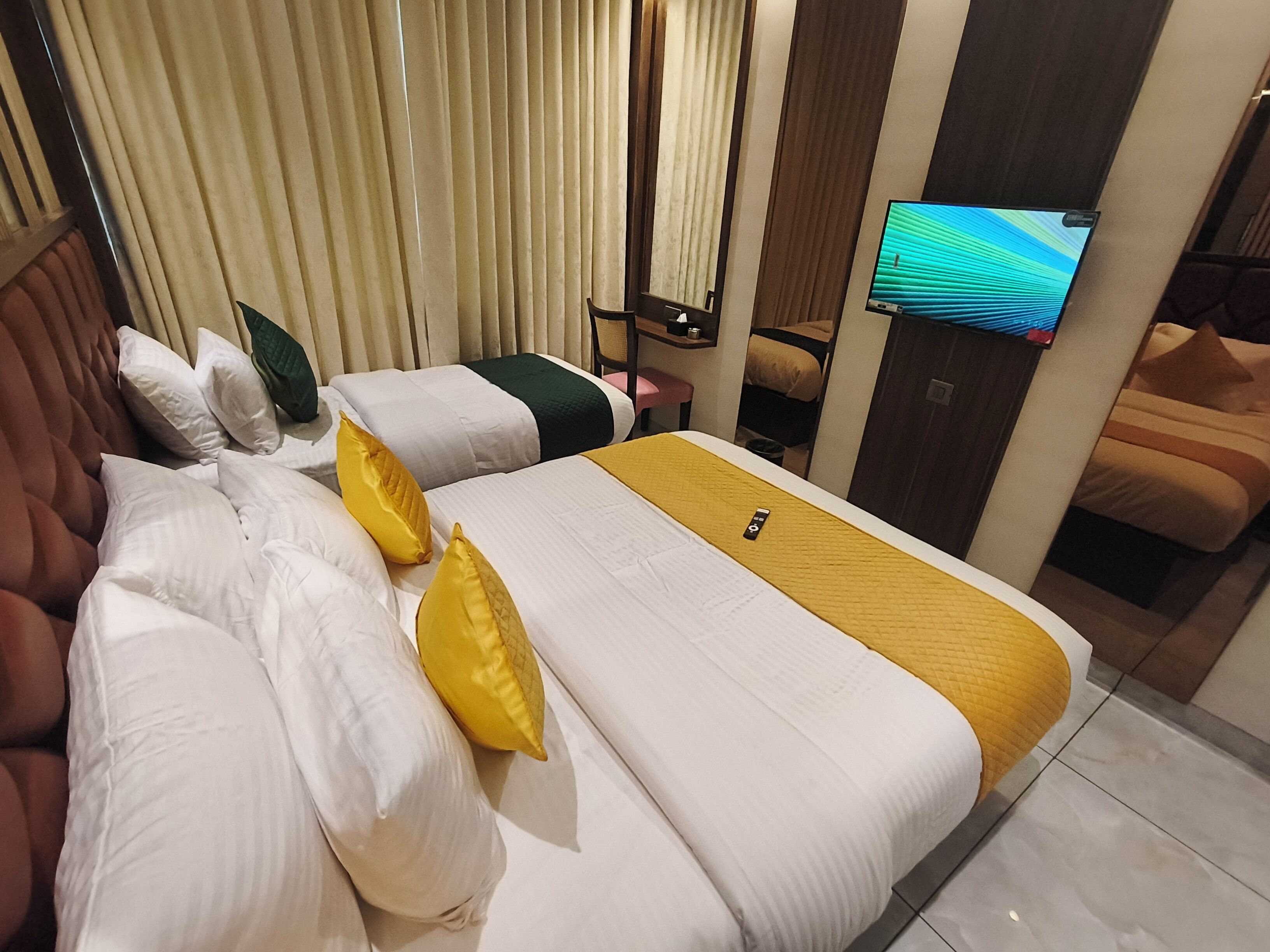 Une chambre d’hôtel avec un grand lit, deux tables de chevet, une télévision et un coin salon comprenant une chaise et un canapé.