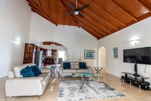 A spacious living room with a high ceiling, a flat-screen TV, and a modern entertainment unit.