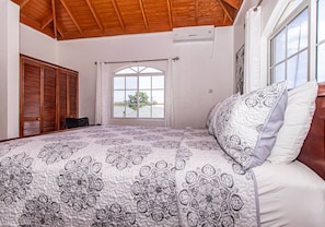 A bedroom with a large bed, a window with a view, and a wooden ceiling.