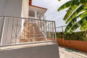 A staircase with a metal railing leading to a white building with a balcony.