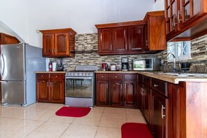Une cuisine avec des meubles en bois, un réfrigérateur en acier inoxydable, une cuisinière et un four à micro-ondes.