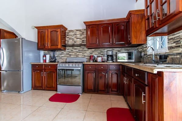 A kitchen with wooden cabinets, a stainless steel refrigerator, a stove, and a microwave.