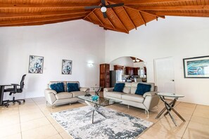 A spacious living room with a high ceiling, a glass coffee table, a sofa, and a dining table.