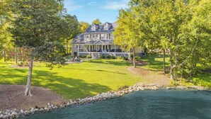 A large, two-story house with a well-maintained lawn and a small pond in the foreground.