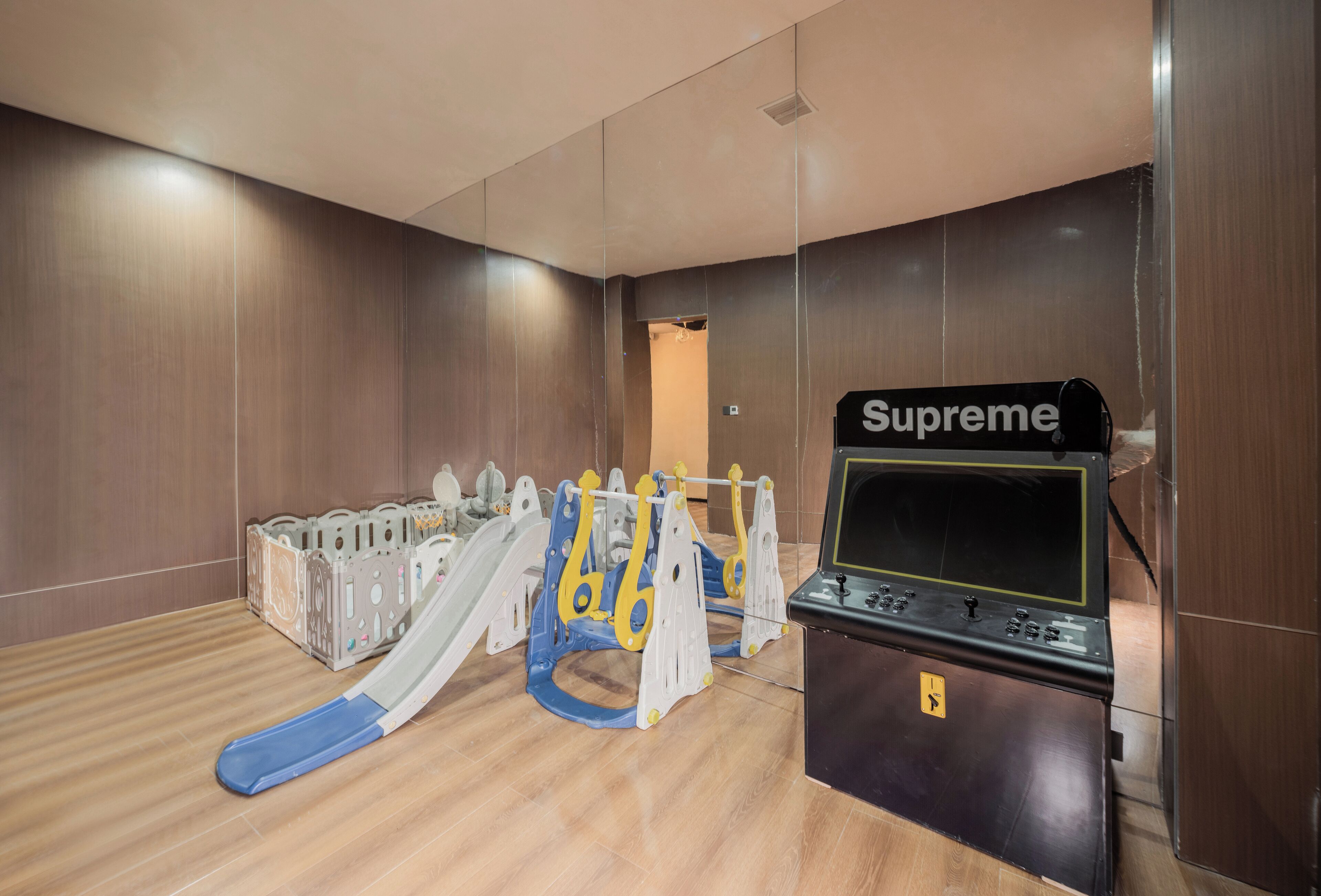 A room with a play area including a slide and a Supreme gaming console.