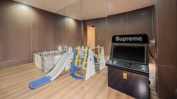 A room with a play area including a slide and a Supreme gaming console.