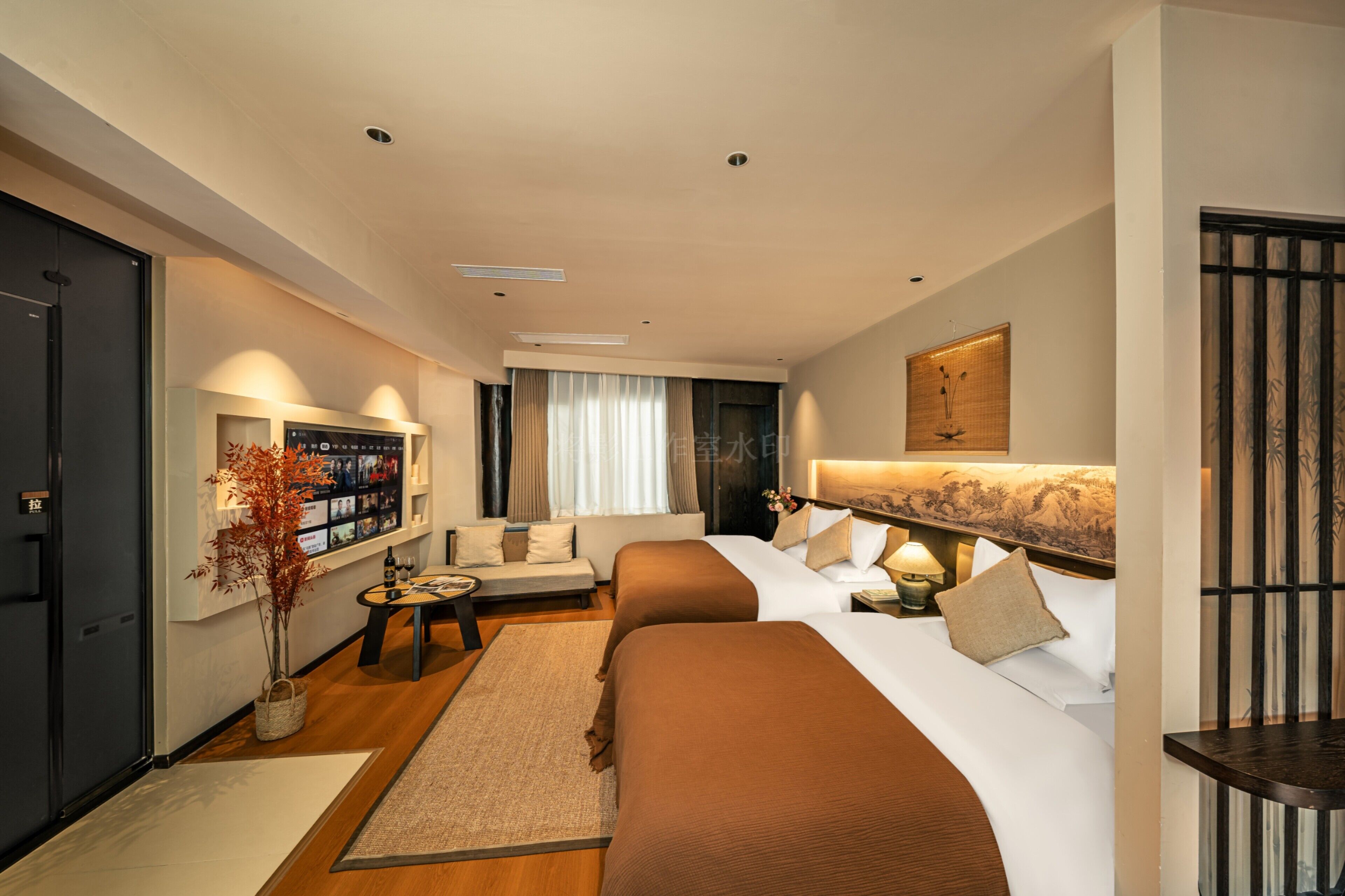 Habitación de hotel con dos camas, un sofá, una mesita, un televisor y un elemento decorativo en la pared.
