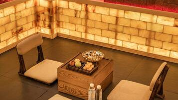 A corner seating area with a wooden bench, a small wooden table with a basket of snacks, and two bottles of water.
