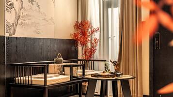 A modern room with a wooden bench, a small round table, and a large window with curtains.