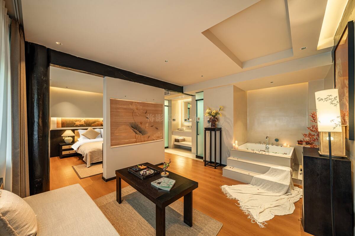 Ein modernes Hotelzimmer mit einem großen Bett, einer Sitzecke mit Tisch, einem Badezimmer mit Badewanne und Blick auf die Stadt.
