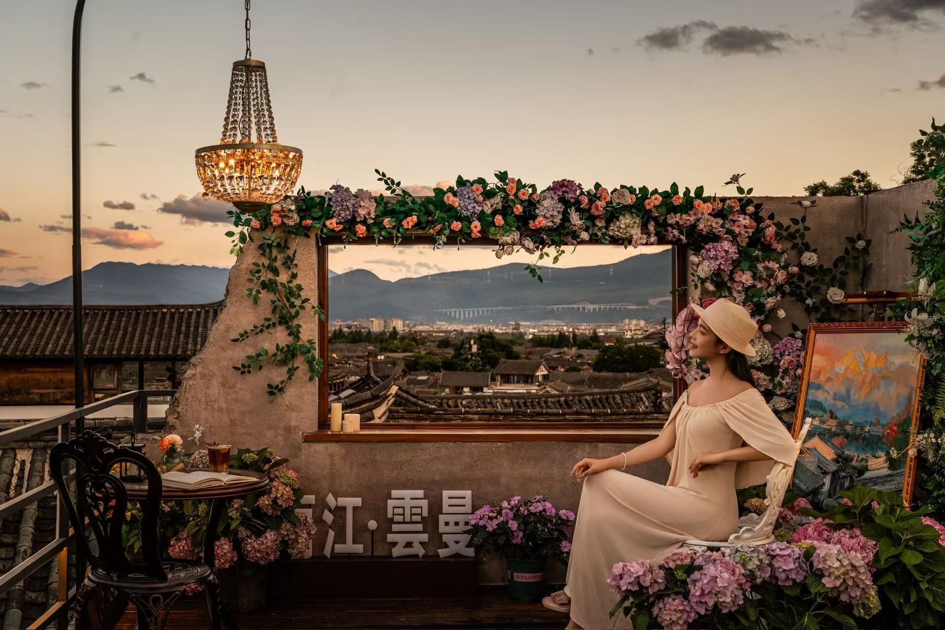 A woman seated in a chair with a view of a cityscape and mountains in the background.