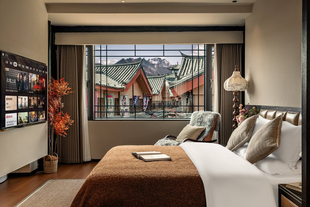 Ein Hotelzimmer mit großem Fenster und Blick auf traditionelle Architektur und Berge.