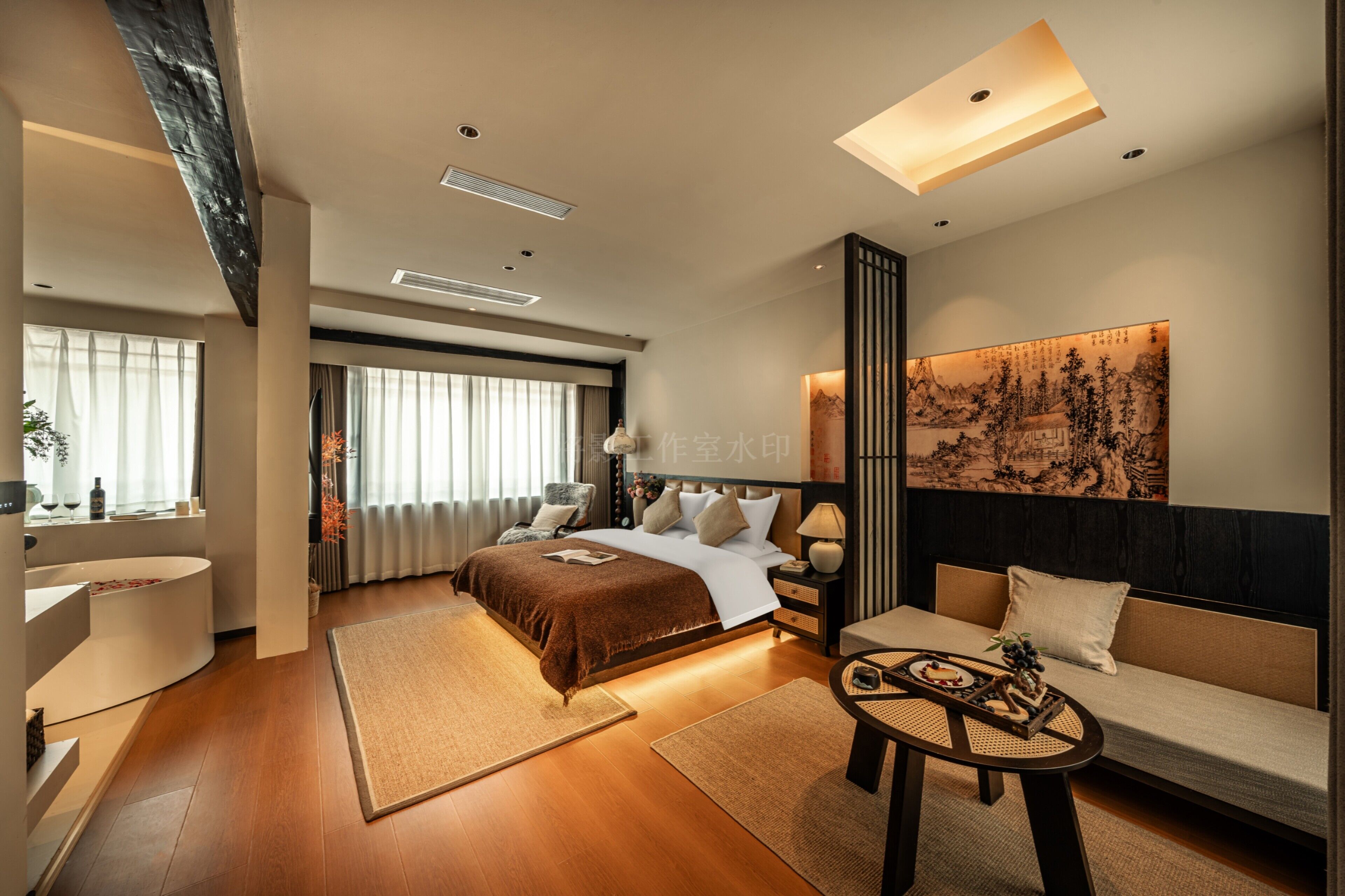 A modern hotel room with a large bed, a sofa, a small table, and a bathroom area.