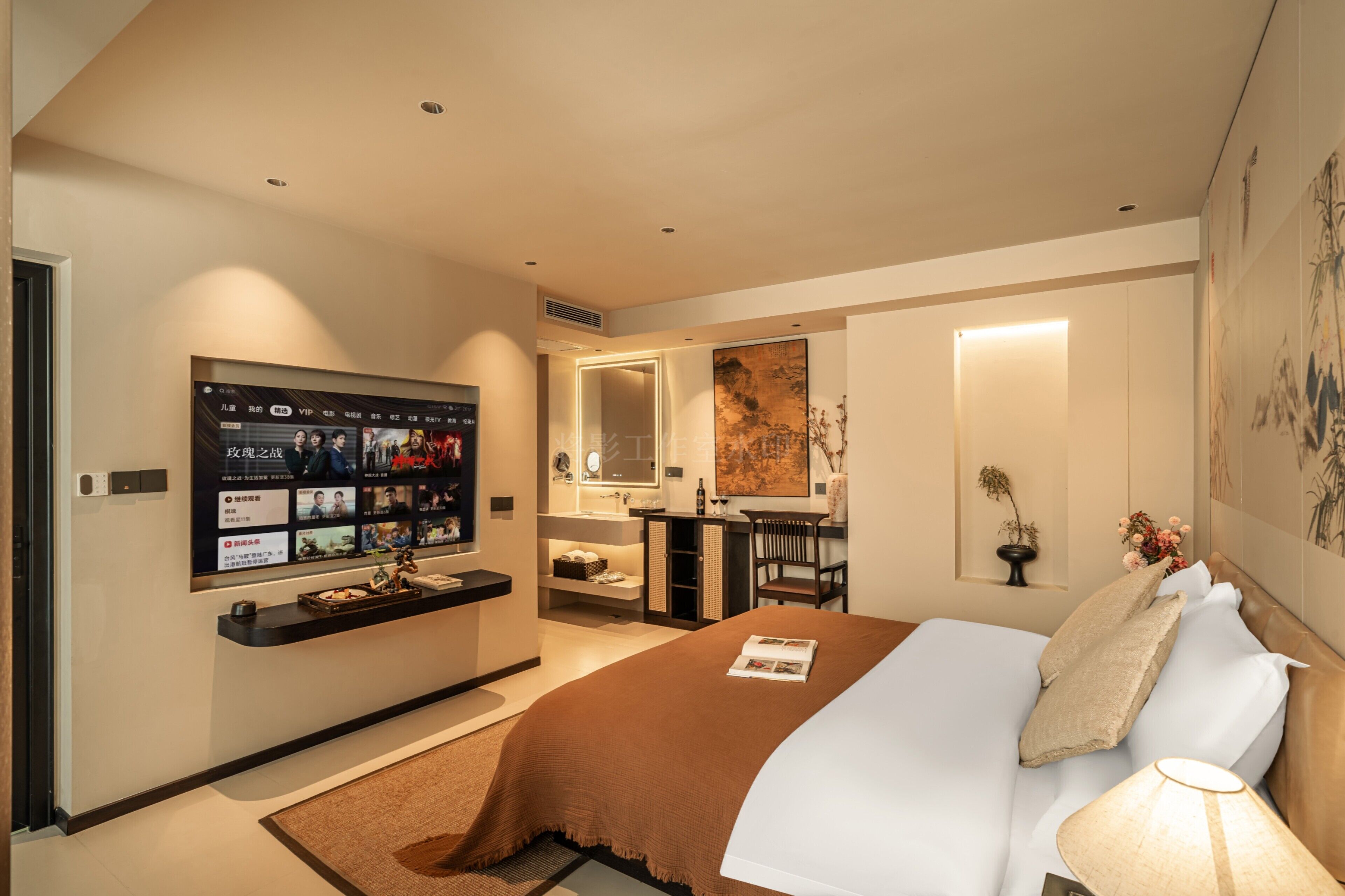 Une chambre d’hôtel moderne dotée d’un grand lit, d’un téléviseur fixé au mur, d’un bureau avec une chaise et d’une salle de bain avec un miroir et un lavabo.