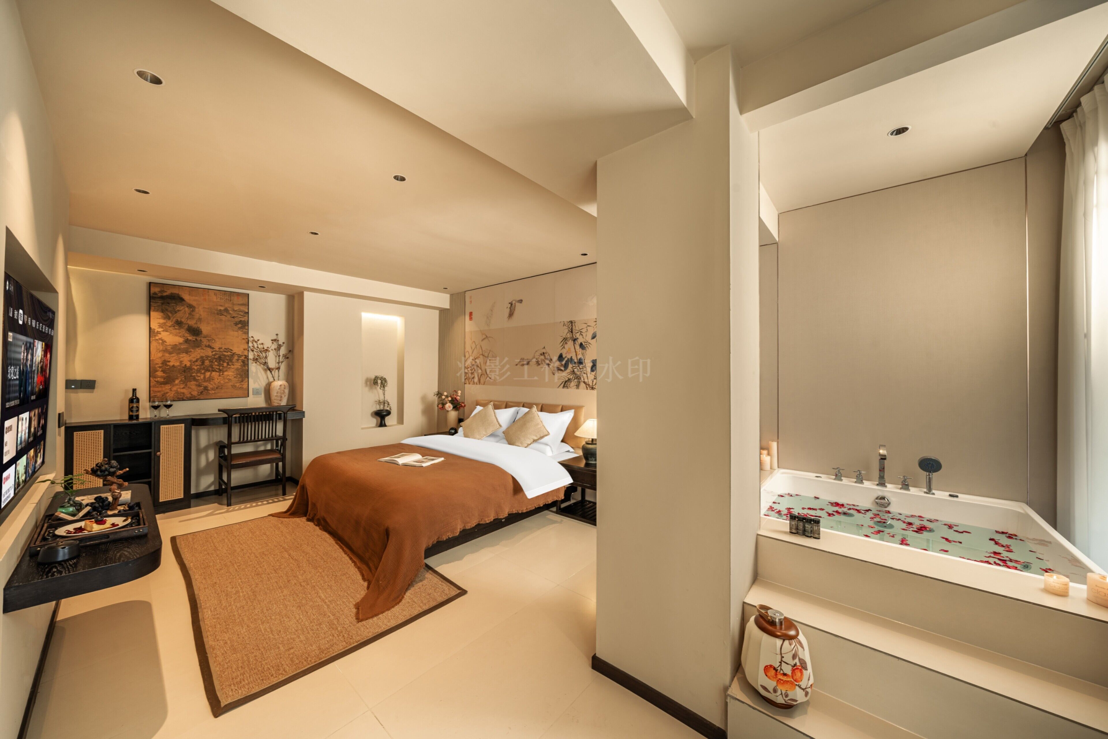A modern bedroom with a large bed, a desk, and a bathroom with a bathtub.