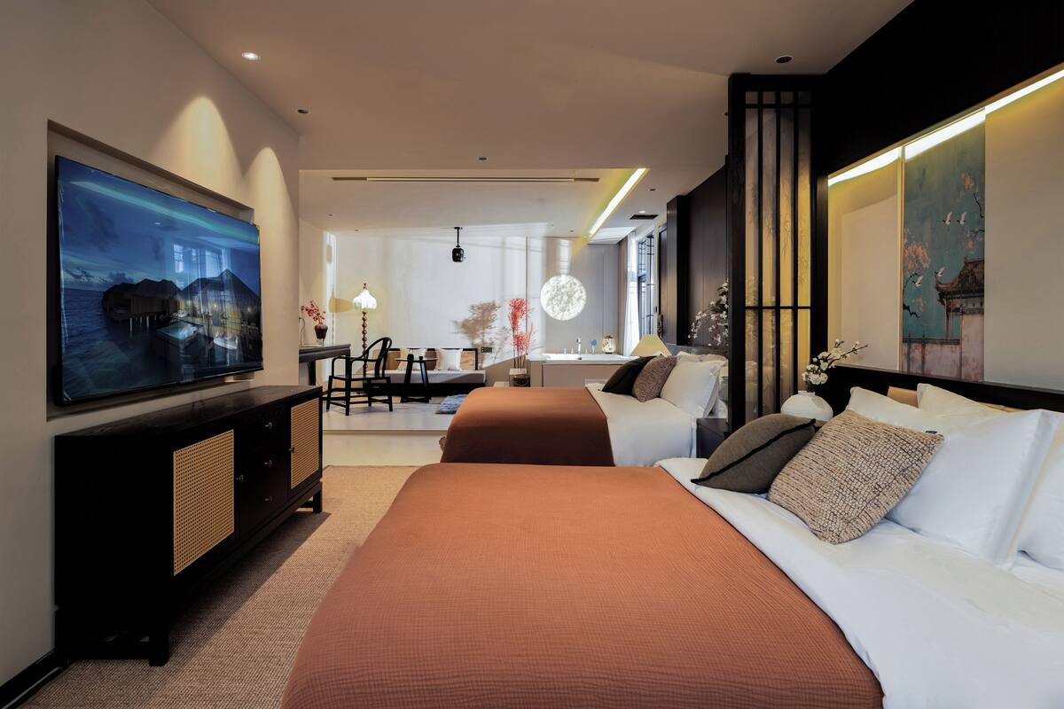 Ein modernes Hotelzimmer mit einem großen Bett, einem Schreibtisch und einem an der Wand befestigten Fernseher.