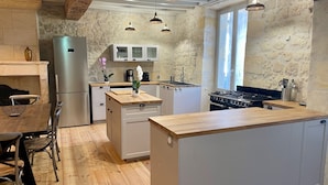 Une cuisine moderne dotée d’un plan de travail en bois, d’appareils électroménagers en acier inoxydable et d’un mur de crédence en pierre.