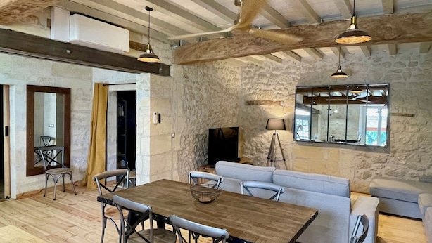 Un intérieur rustique avec des murs en pierre apparentes, une table à manger en bois et un canapé.