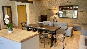 Un salon chaleureux avec un mur en pierre, une table à manger en bois et un canapé.