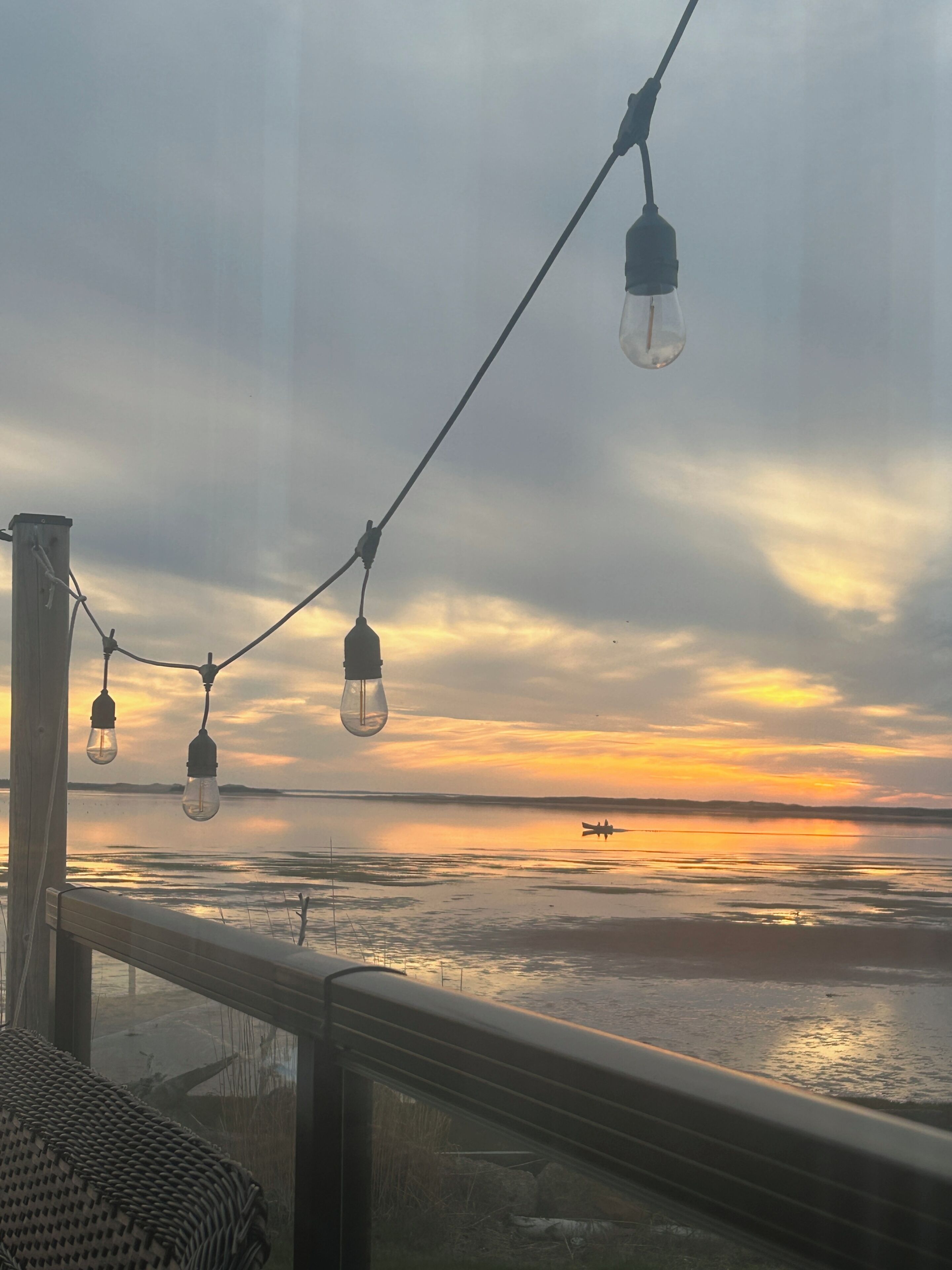 A sunset view from a balcony with string lights.