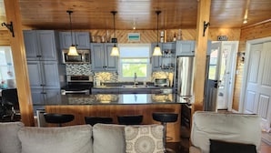A modern kitchen with grey cabinets, a central island, and pendant lighting.